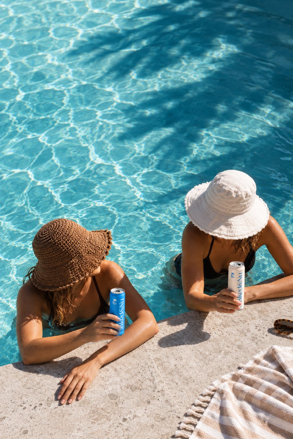 Two friends poolside sipping Naked & Nu cans
